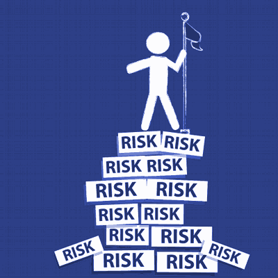 A cartoon man stands triumphantly on top of a pile of signs which all say 'Risk'.